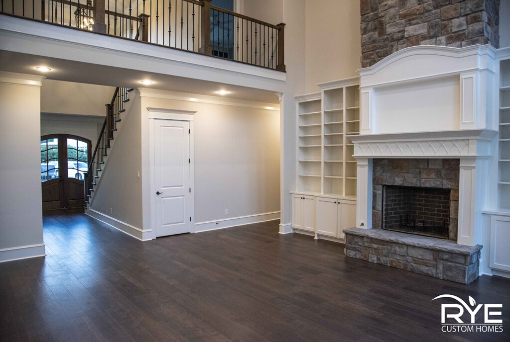 Custom home interior in Benton, Arkansas featuring a fireplace with built-ins, framed TV, and catwalk entry by Rye General Contractors