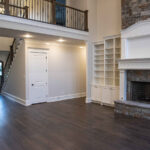 Custom home interior in Benton, Arkansas featuring a fireplace with built-ins, framed TV, and catwalk entry by Rye General Contractors