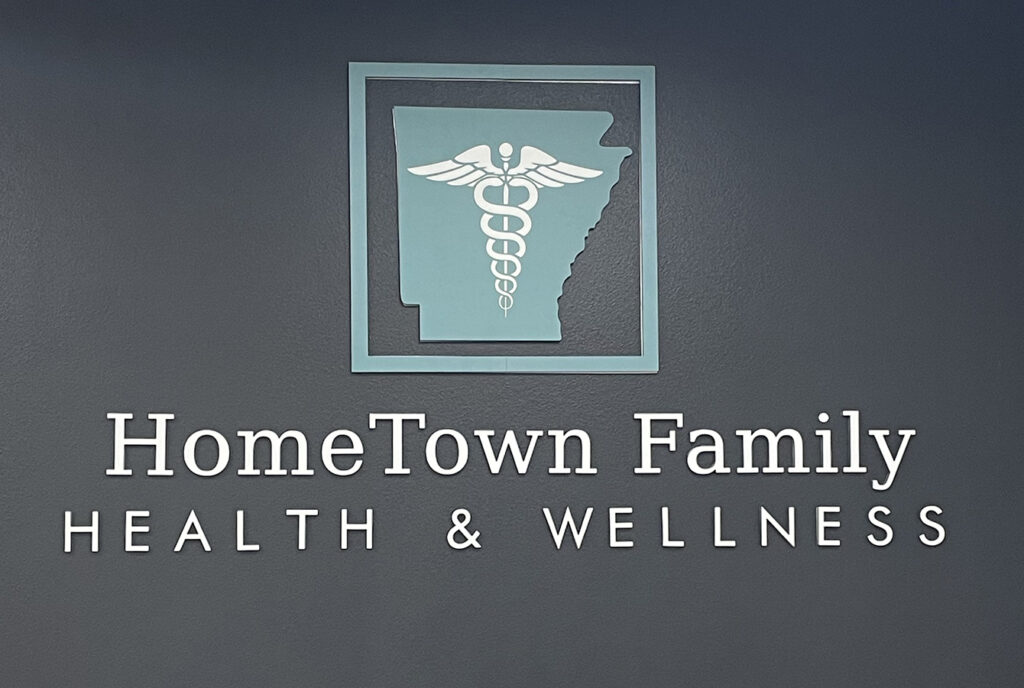 Reception and check-in area at Hometown Health and Wellness clinic in Benton, Arkansas featuring a logo wall and welcoming entry by Rye General Contractors
